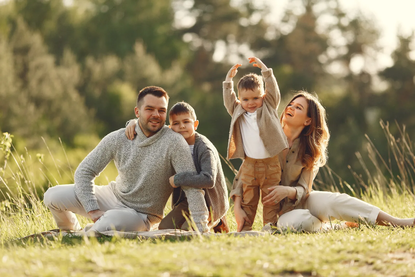 Una familia de cuatro juega sentada en el césped en un día de sol